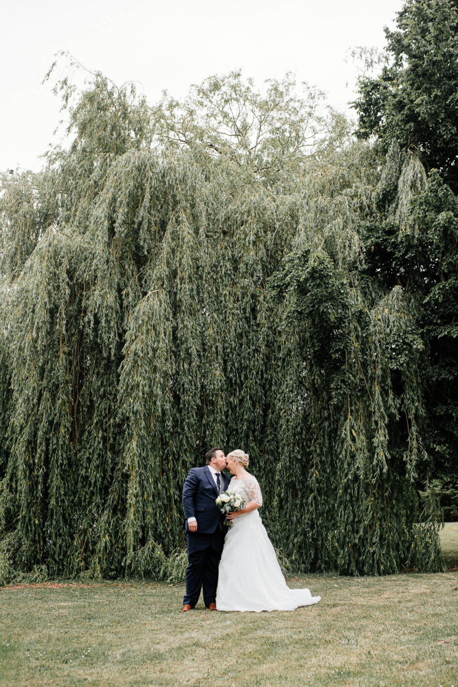 Bride and groom kissing under a willow tree at Holiday Inn in Warmsworth.