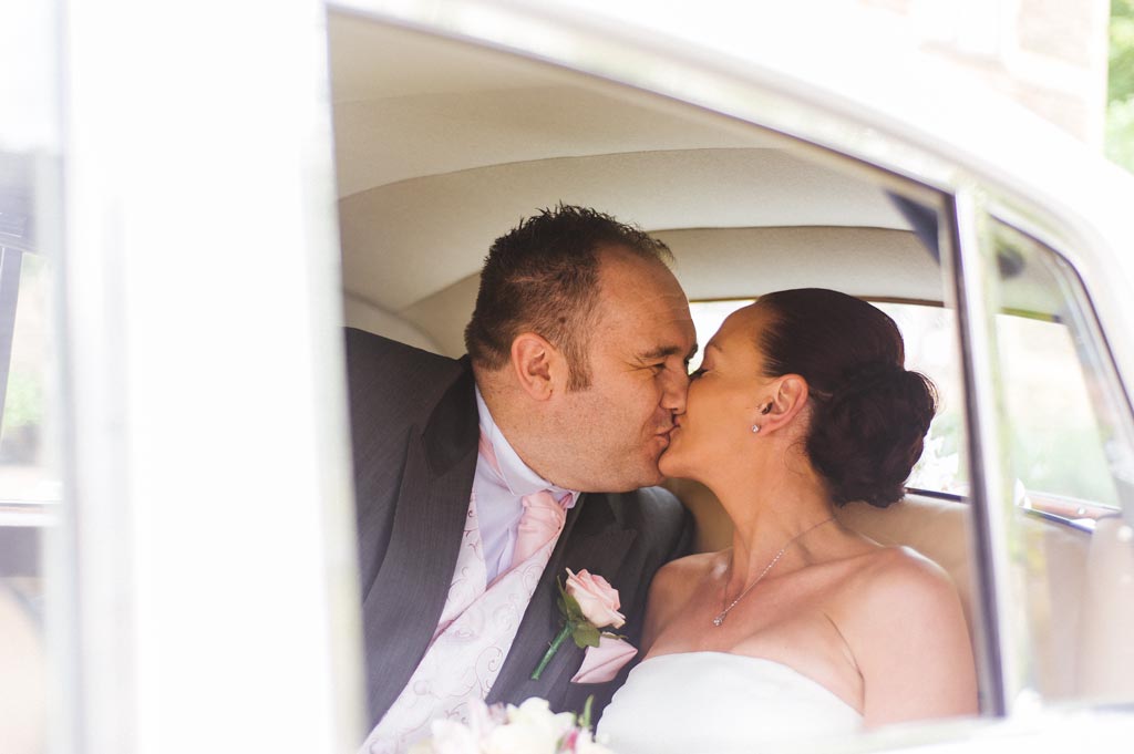 Newlyweds kissing in a wedding car