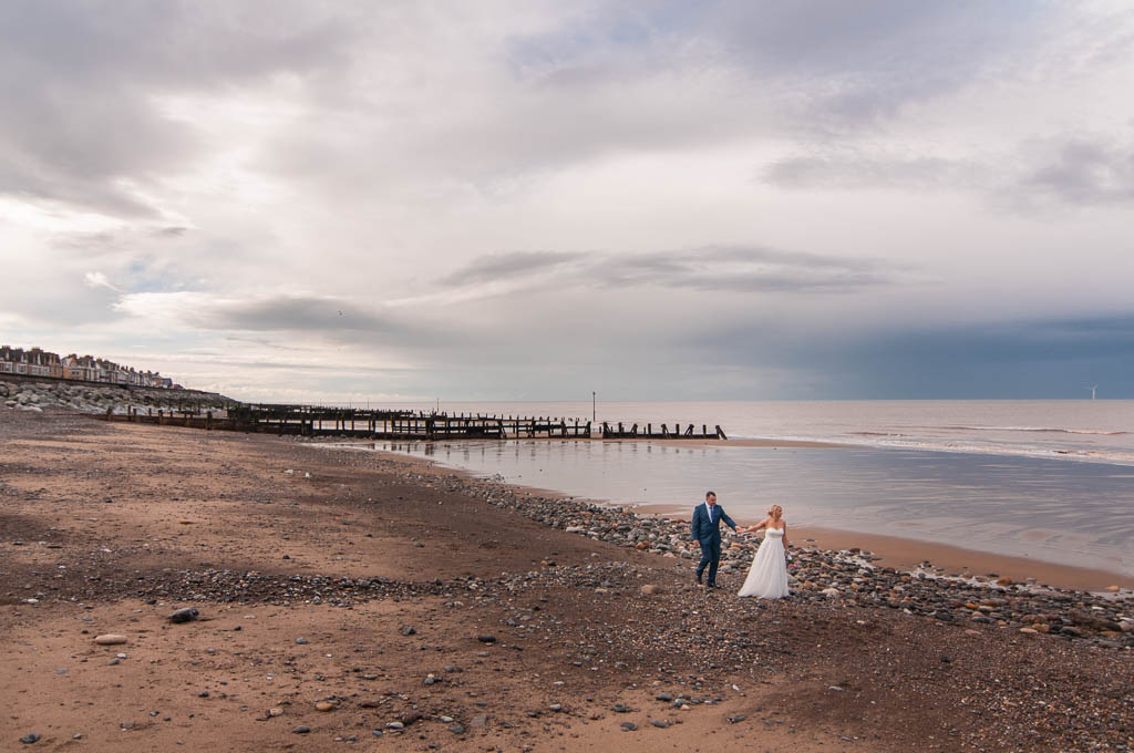 Bride and groom walking on a beach in Withernsea