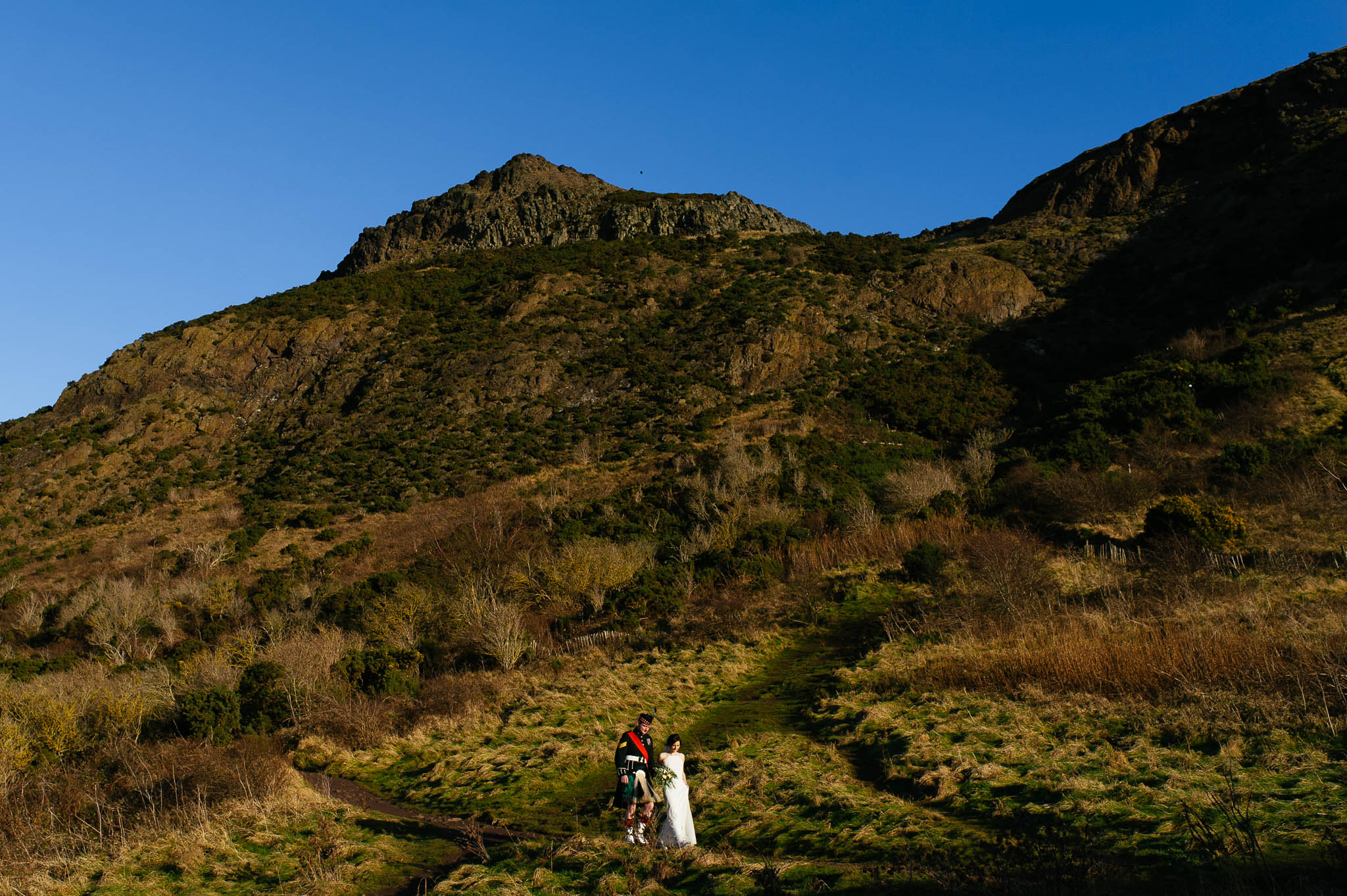 Bride and groom climbing Arthur's Seat in Edinburgh