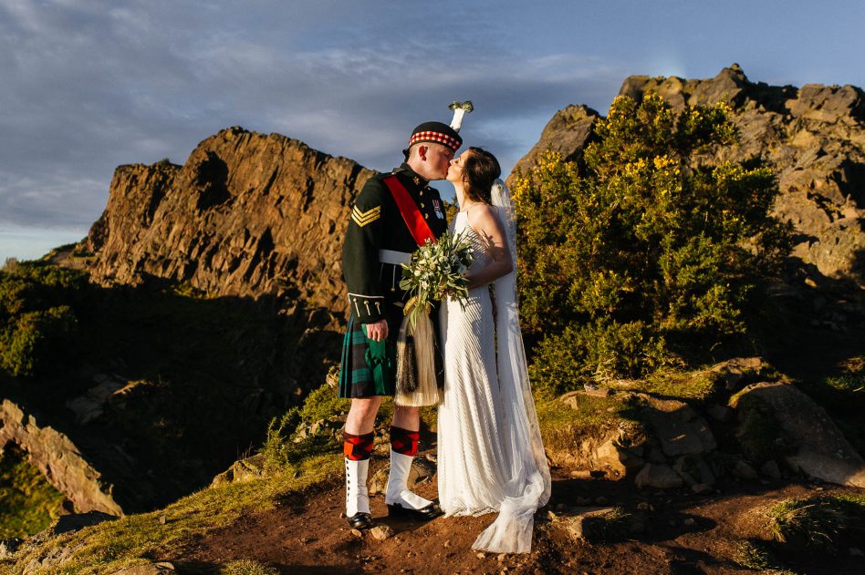 Newly weds kissing on top of a Scottish mountain, Edinburgh wedding photographer.