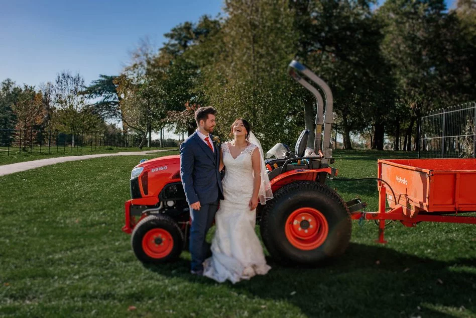 Bride and groom posing with a tractor at Cusworth Hall