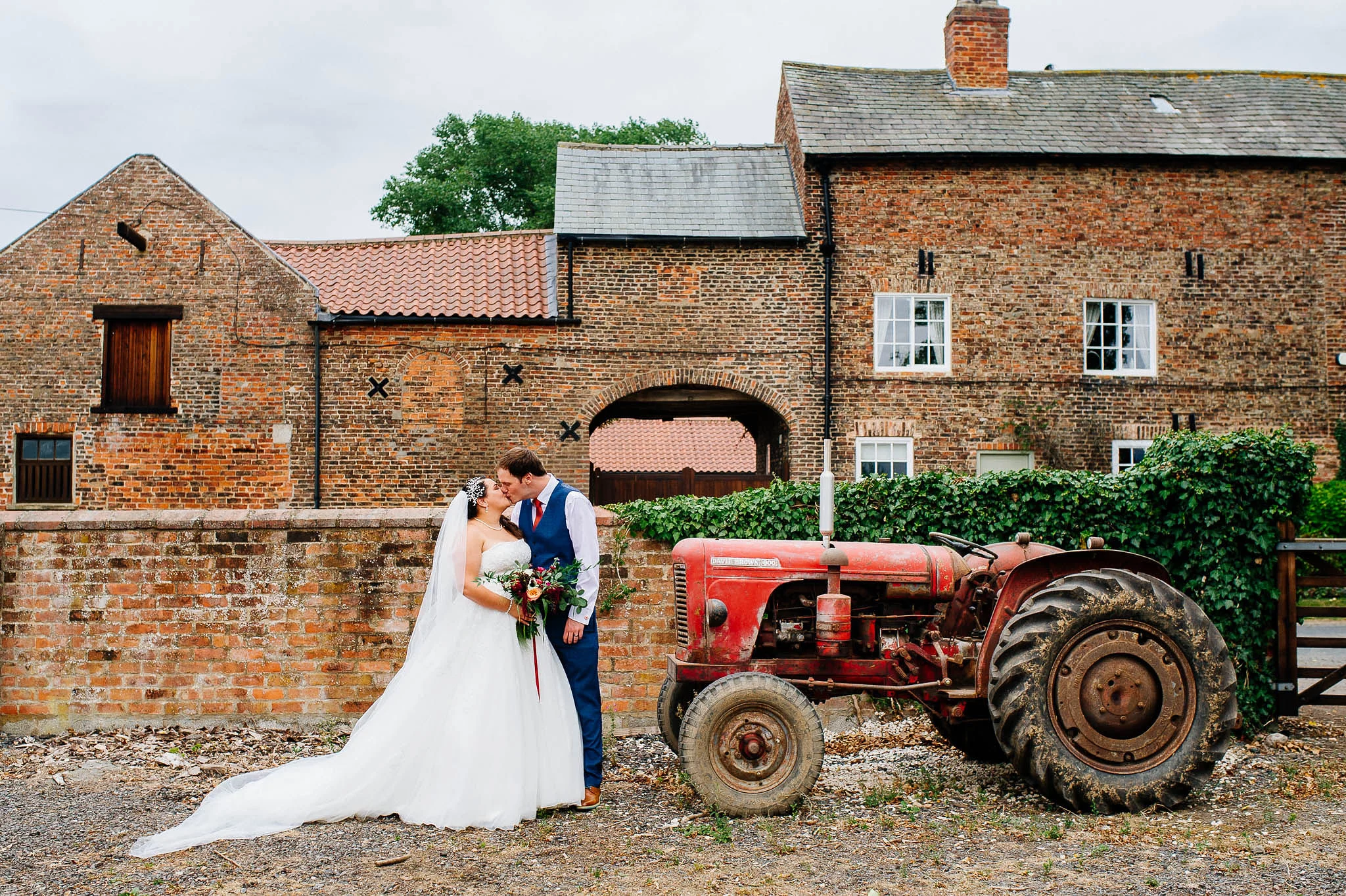 Bride and groom with a tractor outside The Normans Wedding Venue