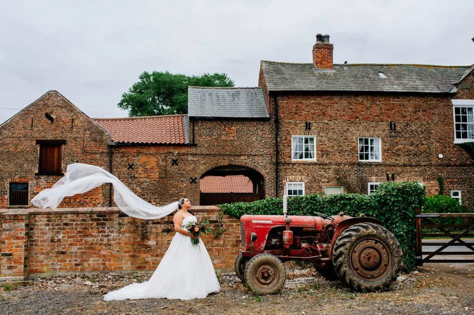 Bride with tractor outside The Normans wedding venue