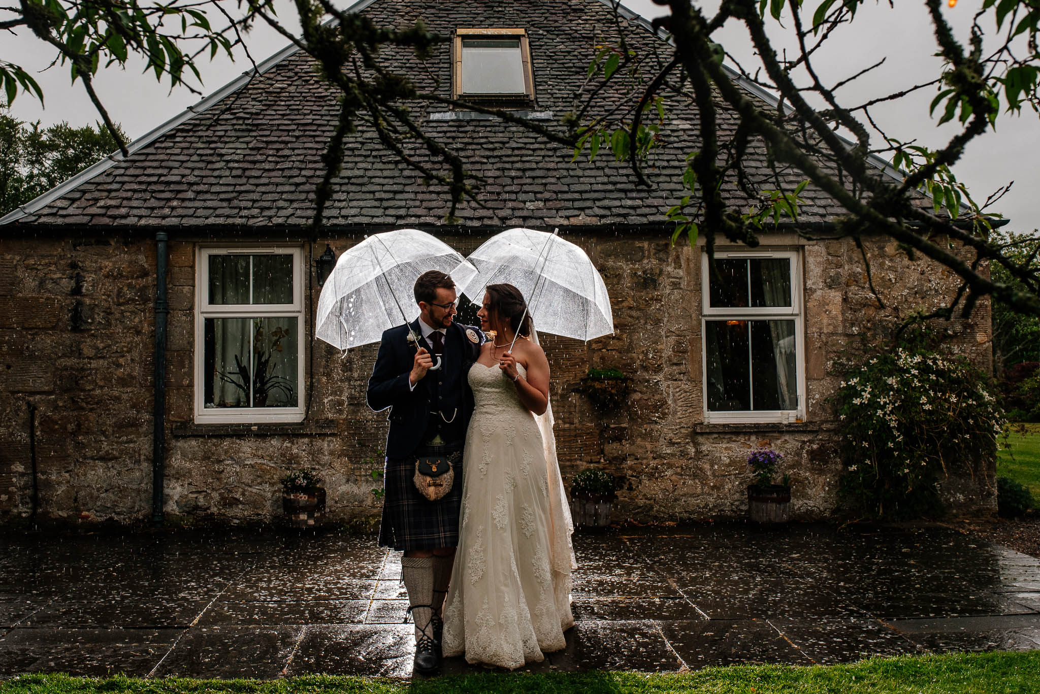 Bride and groom holding white umbrellas on a rainy Edinburgh wedding.