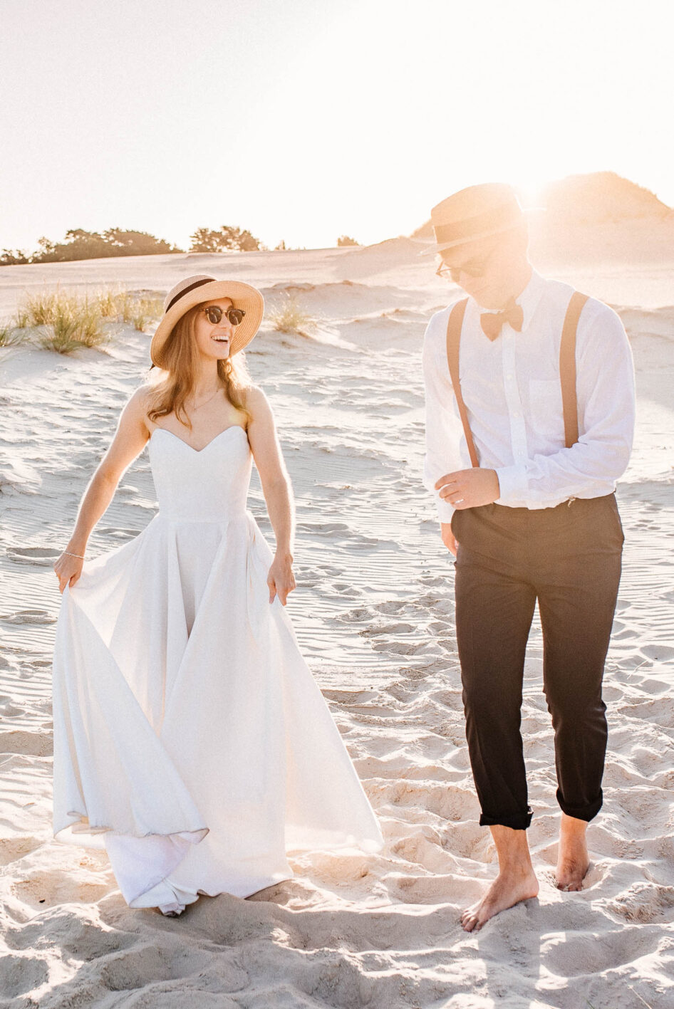 Happy couple dancing on a sand dune at sunrise.