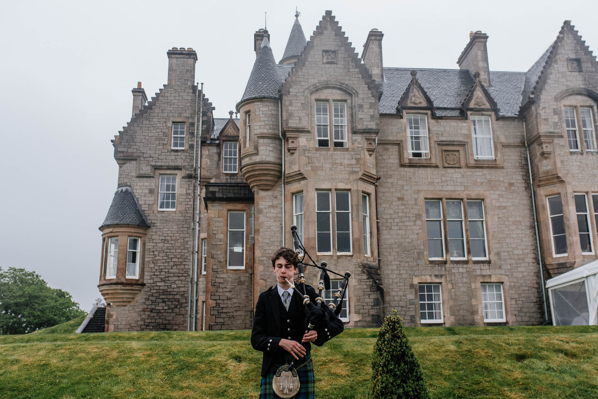 A Scottish piper providing entertainment during an outdoor wedding in the UK