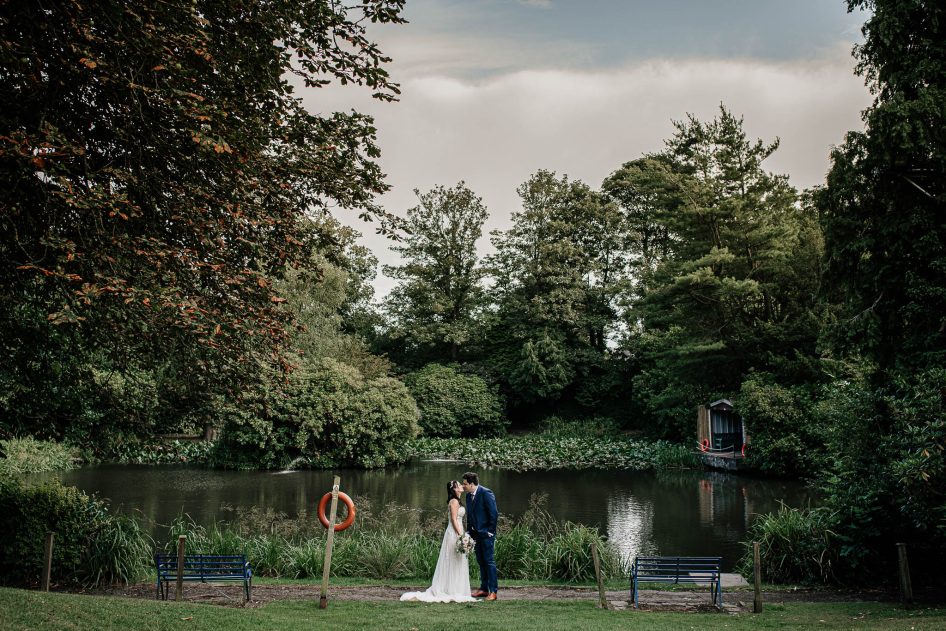 Bride and groom kissing near the pond outside Kenwood Hall