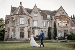 Bride and groom holding hands walking in front of Kenwood Hall wedding venue