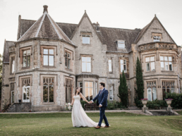 Bride and groom holding hands walking in front of Kenwood Hall wedding venue